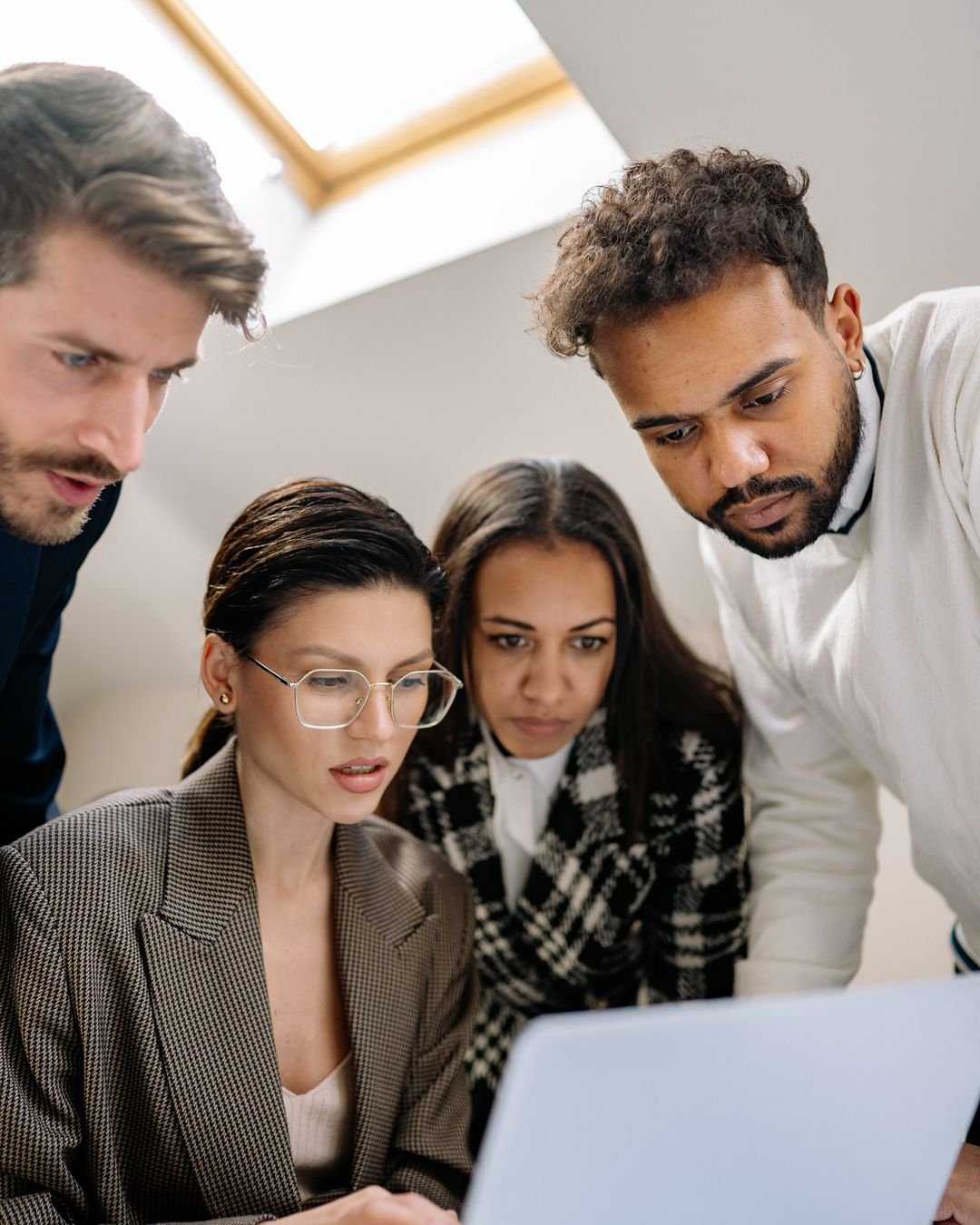 A diverse group of professionals collaborating on a laptop at work.