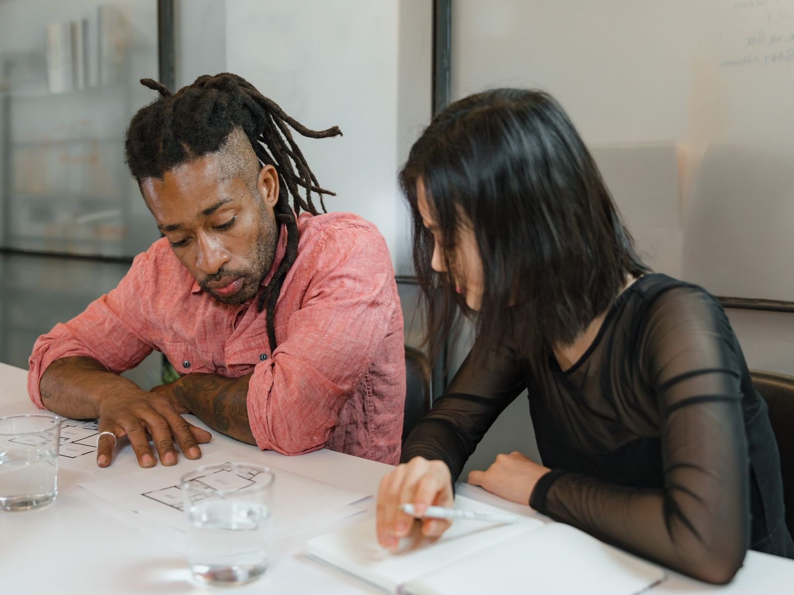 Two colleagues collaborate on design plans in a modern office setting. Focus on teamwork.
