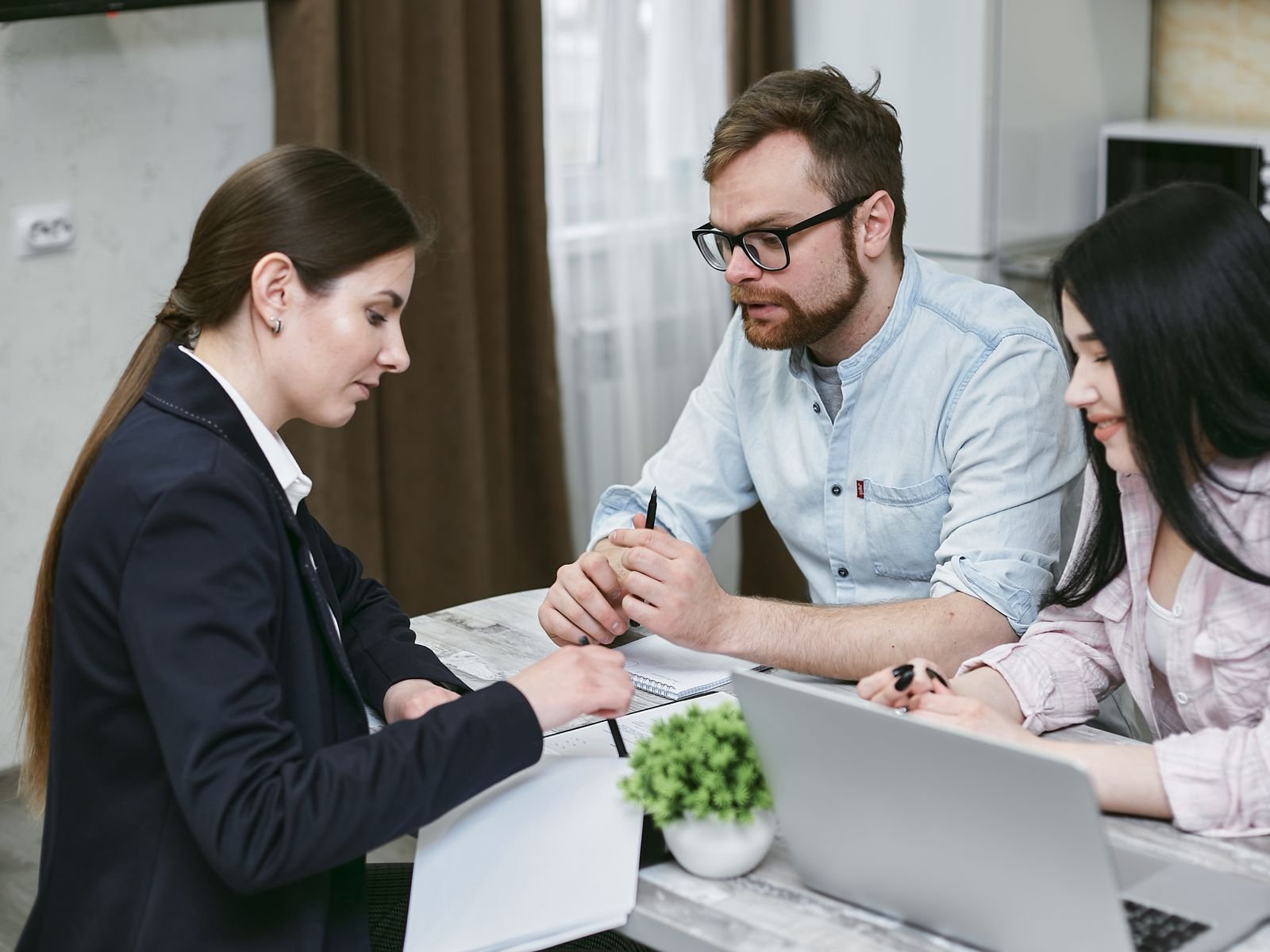 A couple discusses financial documents with their advisor, highlighting investment strategies.