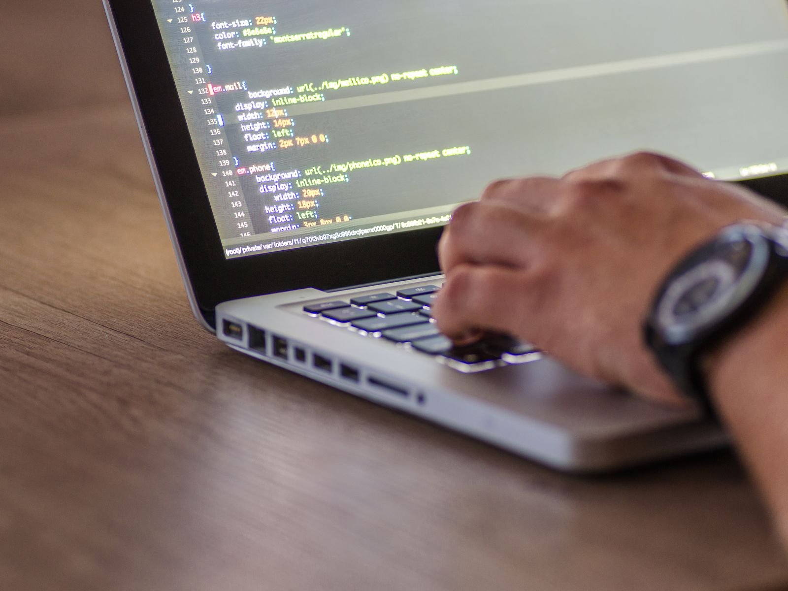 A close-up shot of a person coding on a laptop, focusing on the hands and screen.